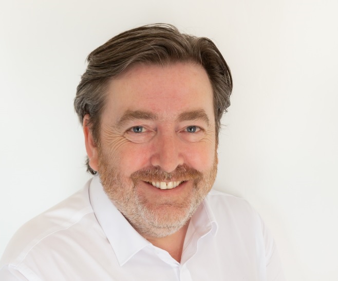 Pay by phone slots: the future of mobile gaming? 25 Warm smiling man with beard and white shirt, professional portrait for branding on smashing life website.